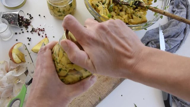 Personal perspective of woman hands preparing Amanita caesarea (known as Caesar's mushroom). Put the mushrooms in jars in oil