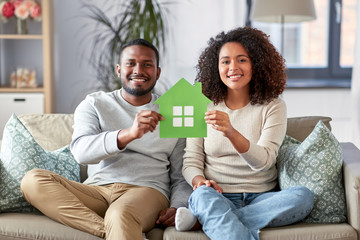 relations and people concept - happy african american couple sitting on sofa at home
