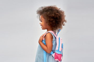 childhood, school and education concept - happy little african american girl with backpack over grey background