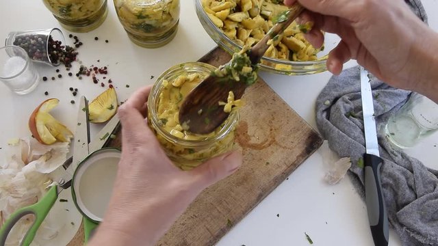 Personal perspective of woman hands preparing Amanita caesarea (known as Caesar's mushroom). Put the mushrooms in jars in oil