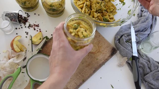 Personal perspective of woman hands preparing Amanita caesarea (known as Caesar's mushroom). Put the mushrooms in jars in oil