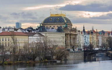 Deurstickers Prague National Theater is located on the Vltava Embankment. A star-blue dome is crowned with a golden crown. From the embankment side the theater is decorated with statues of Wagner and Myslbek © TATIANA