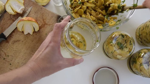 Personal perspective of woman hands preparing Amanita caesarea (known as Caesar's mushroom). Put the mushrooms in jars in oil