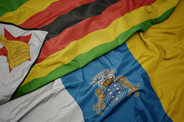 waving colorful flag of canary islands and national flag of zimbabwe.