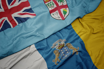 waving colorful flag of canary islands and national flag of Fiji .