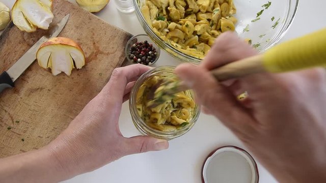 Personal perspective of woman hands preparing Amanita caesarea (known as Caesar's mushroom). Put the mushrooms in jars in oil
