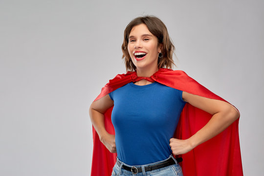 women's power and people concept - happy woman in red superhero cape over grey background