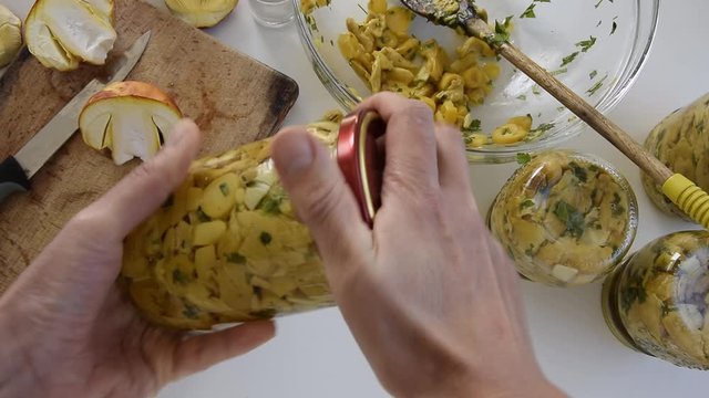 Personal perspective of woman hands preparing Amanita caesarea (known as Caesar's mushroom). Put the mushrooms in jars in oil
