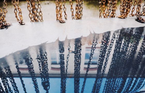 Row of chains reflecting in puddle