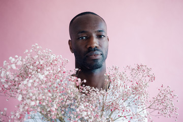 Studio portrait of young man with pink and white flowers