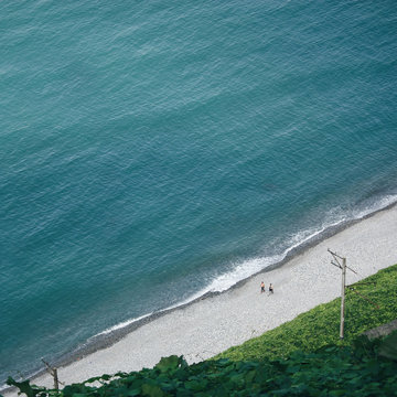 Aerial view of men walking on road along seashore