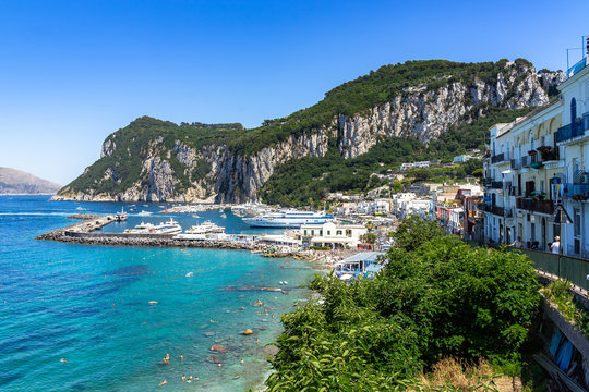 Beautiful view of Marina Grande harbor in Capri lapped by turquoise waters with Punta del Capo in the background, Italy