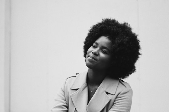 Smiling woman with afro sitting with eyes closed