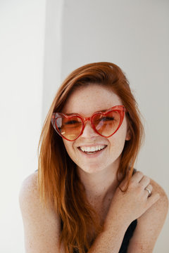 Redhead young woman with heart shaped sunglasses
