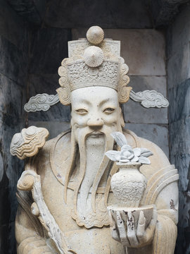 Statue of Confucius holding vase with flower