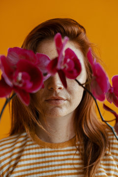 Woman with an orchid covering eyes
