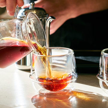 Close up view of tea pouring into glass from kettle