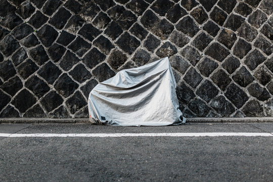 Bike covered with sheet against granite wall