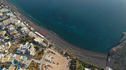 Aerial drone photo of famous seaside village and organised with sun-beds and umbrellas sandy beach of Kamari, Santorini island, Cyclades, Greece