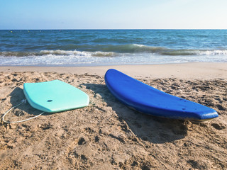 Water surfboards blue and turquoise on the sandy ocean shore with blue water under the endless blue sky