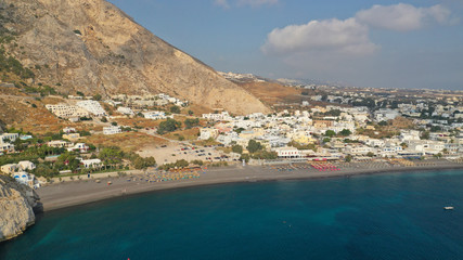 Fototapeta premium Aerial drone photo of famous seaside village and organised with sun-beds and umbrellas sandy beach of Kamari, Santorini island, Cyclades, Greece