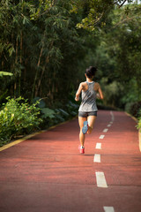 Fototapeta na wymiar Female runner running on park trail . Healthy fitness woman jogging outdoors