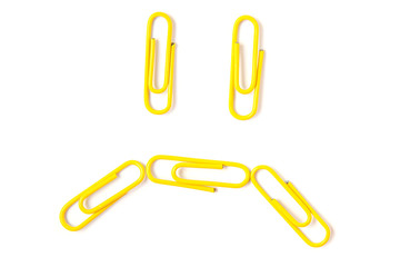 Top view flat lay of yellow paper clips sed emoji isolated on white background.