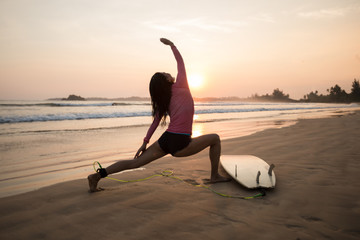 Fototapeta na wymiar Woman surfer warming up on sunset beach.
