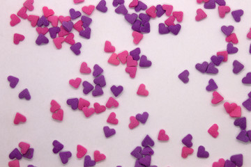 This is a photograph of Pink and Purple heart sprinkles isolated on a White background