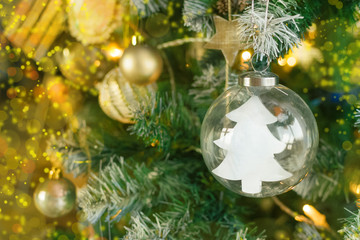 Obraz na płótnie Canvas Decorative Christmas tree on a light background with shiny balls and a glass ball inside which is a Christmas tree with copyspace