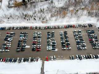 Parking lot filled with cars near commuter train transit at winter. Aerial view. The parking is...