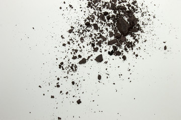 This is a photograph of a Dark Brown powder eyeshadow isolated on a White background