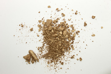 This is a photograph of a shimmery golden powder eyeshadow isolated on a White background