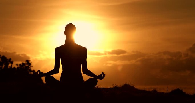 Woman meditating on mountain at sunset. Mind body and spirit concept. 