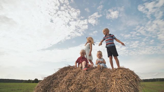 Children launch airplanes standing on a stack of straw.