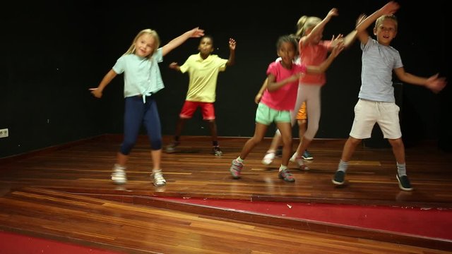Positive children studying modern style dance in class indoors
