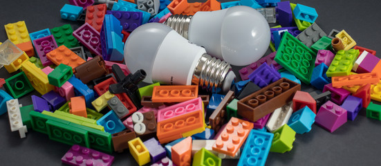 Fototapeta na wymiar two bulbs light and plastic blocks toys