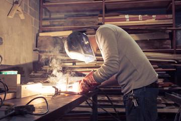 Man wearing work clothes full face shield safety helmet workshop mask and blow torch tig welding ...