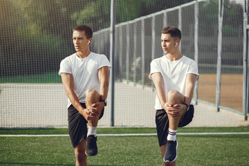 Men in a city. Guys in a sports clothes. Friends training on a grass