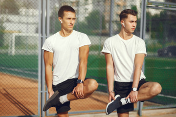 Men in a city. Guys in a sports clothes. Friends training on a grass