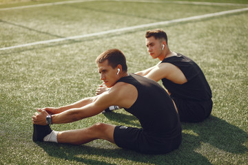 Men in a city. Guys in a sports clothes. Friends training on a grass