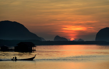 Sailigh fishing boat on orange surface sea with sunrise background in twilight time