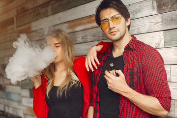 Stylish couple in a city. Two people use the electronic cigarette