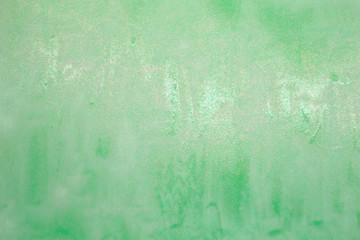 This is a photograph of a Green shiny Lip gloss swatch background