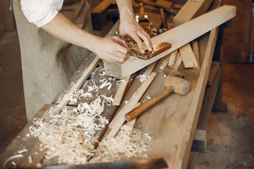 Man working with a wood. Carpenter in a white shirt