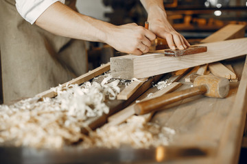 Man working with a wood. Carpenter in a white shirt