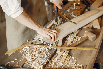 Man working with a wood. Carpenter in a white shirt