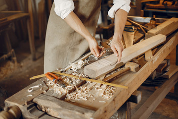 Man working with a wood. Carpenter in a white shirt