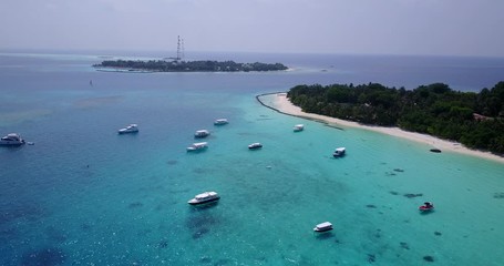 Drone flying over tour boats and yachts anchored on calm lagoon in Louisiade Archipelago, Papua New Guines