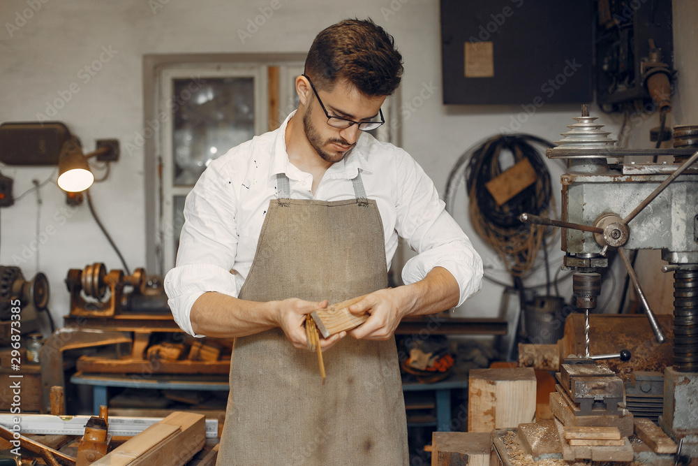 Wall mural Man working with a wood. Carpenter in a white shirt